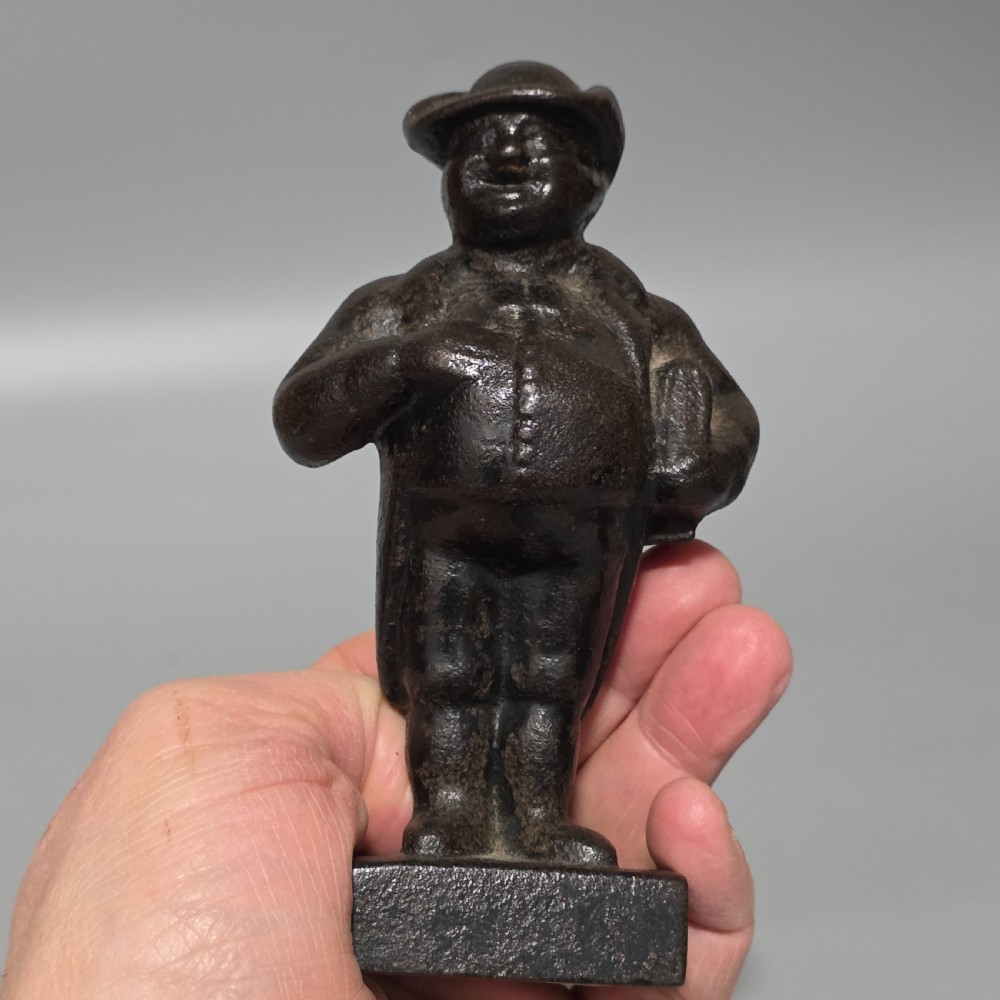 A dark cast iron paperweight depicting a standing nineteenth-century gentleman on a square plinth base. View VIII