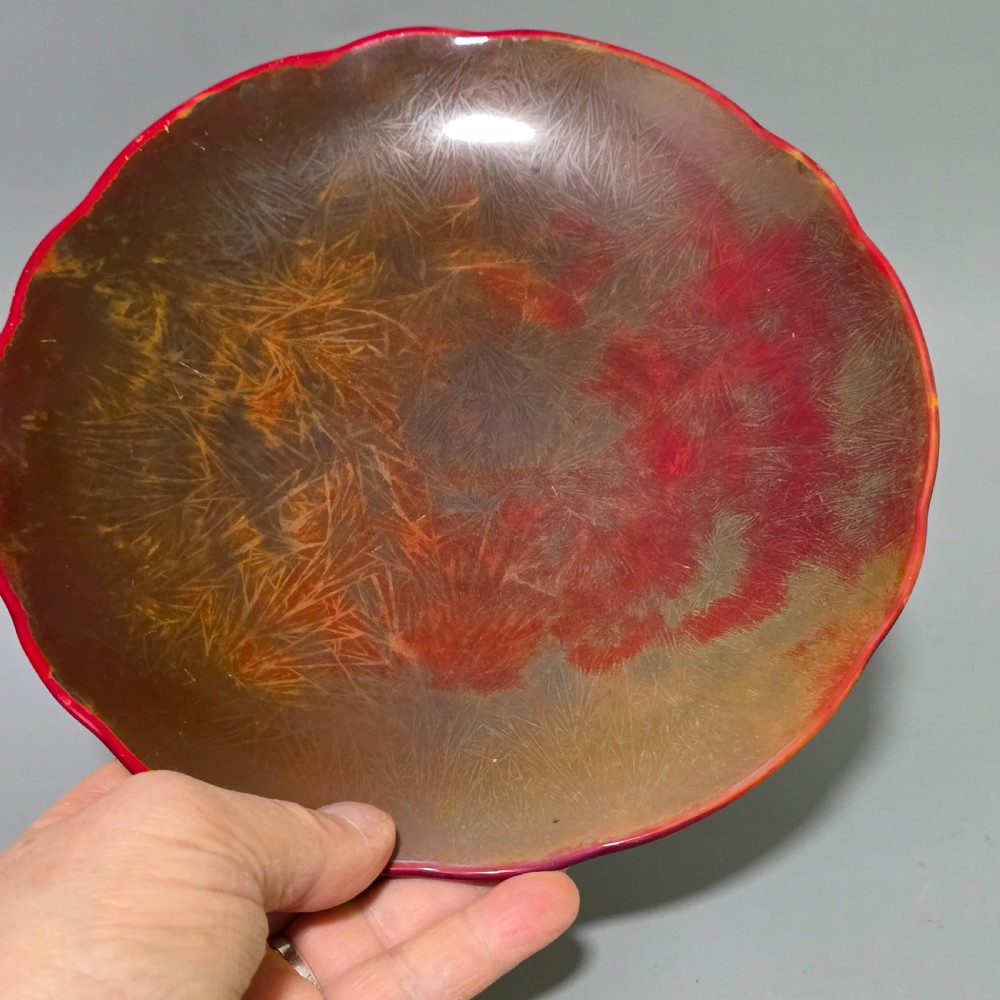 A shallow ceramic art pottery plate featuring a crimson red flambe glaze combined with golden-brown crystalline textures and a scalloped edge. View VIII