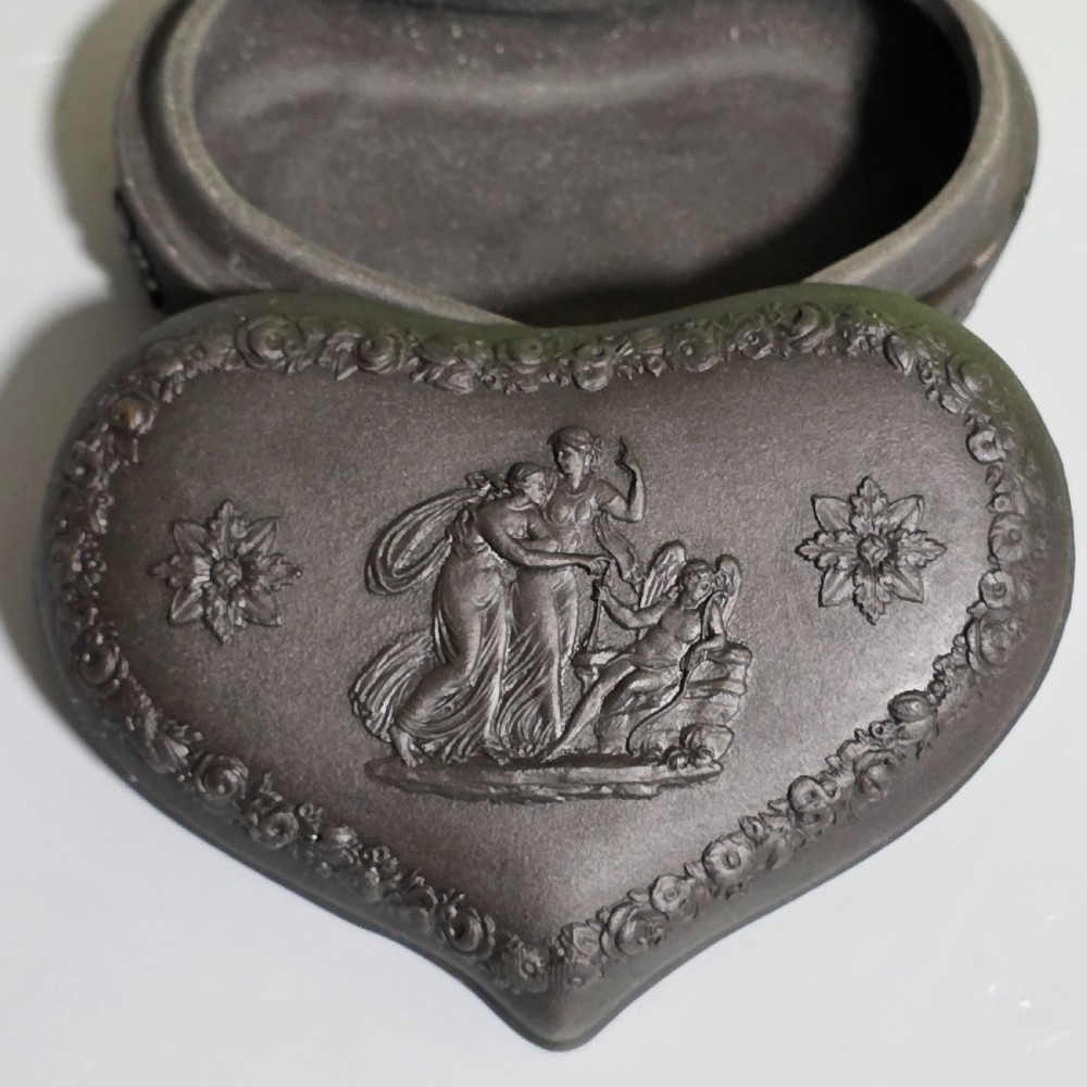 A kidney-shaped matte black basalt stoneware trinket box featuring Neoclassical relief figures, rosettes, and floral garland borders. View VIII