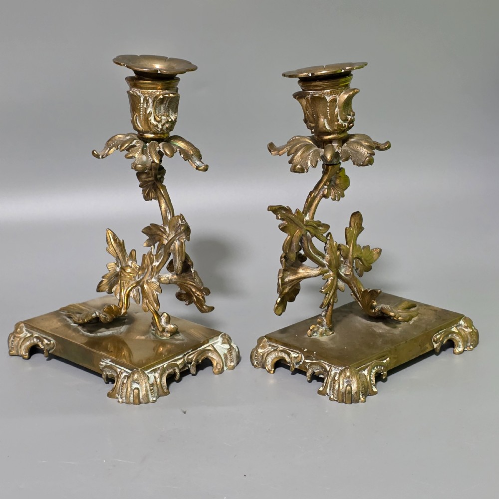 A pair of 19th-century French Napoleon III cast brass candlesticks featuring ornate scrolling leaf motifs and rectangular bases. View II
