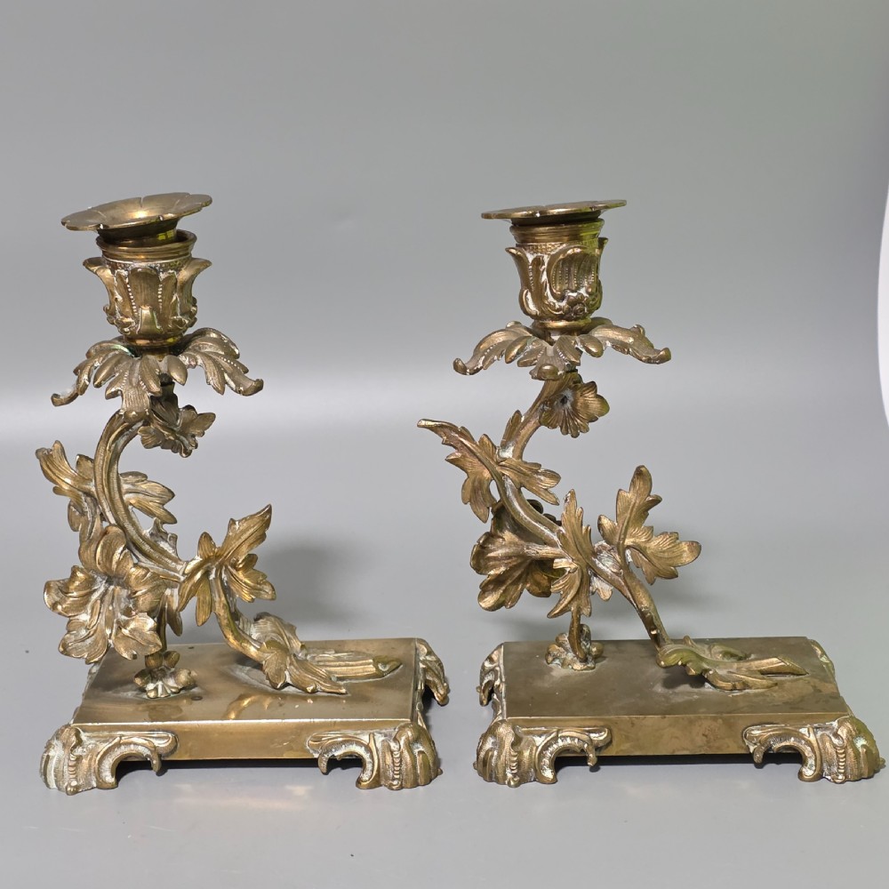 A pair of 19th-century French Napoleon III cast brass candlesticks featuring ornate scrolling leaf motifs and rectangular bases. View IV