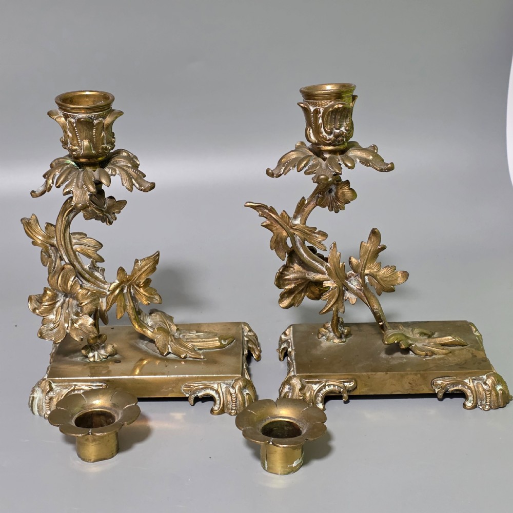 A pair of 19th-century French Napoleon III cast brass candlesticks featuring ornate scrolling leaf motifs and rectangular bases. View X