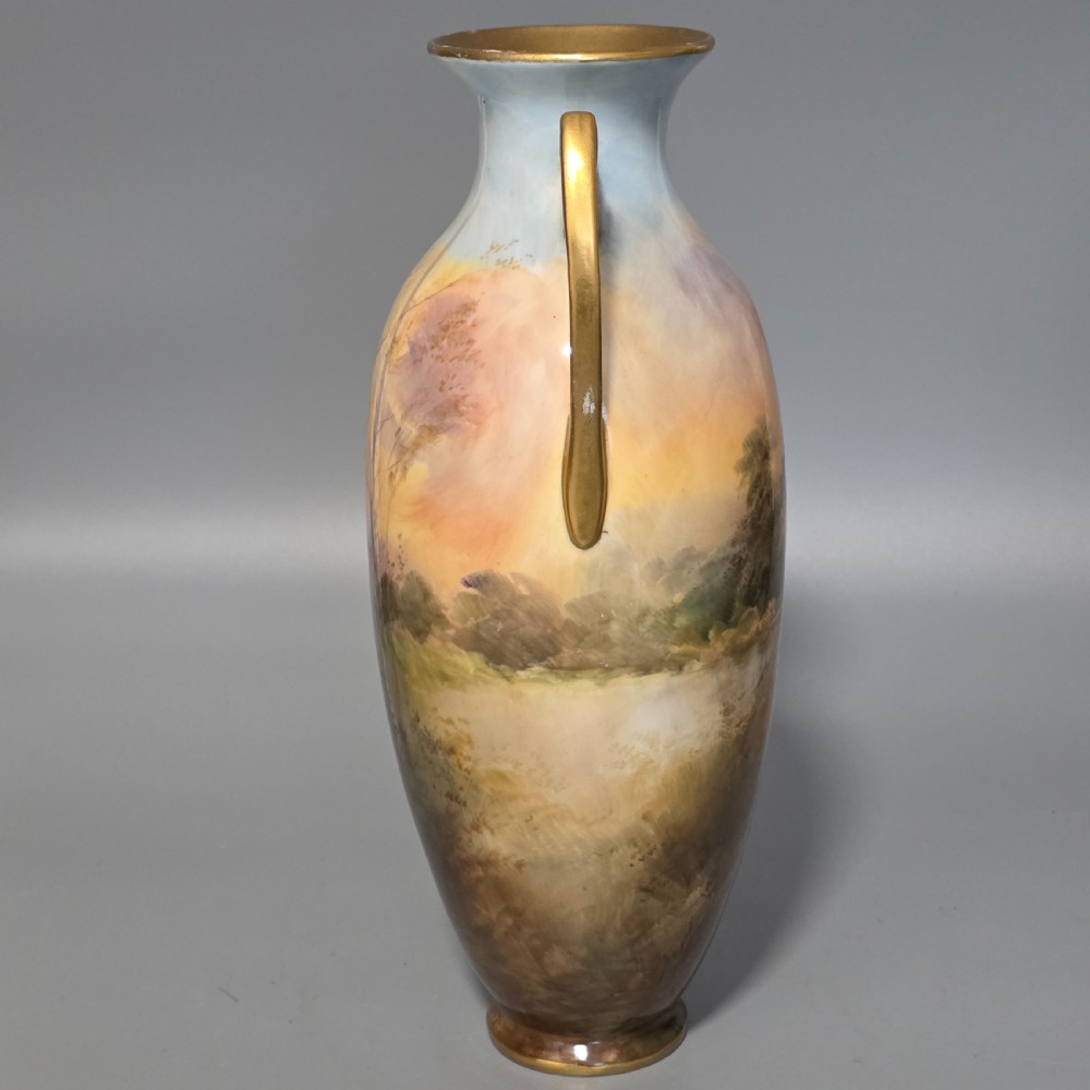 A tall porcelain vase featuring twin gilded handles and a handpainted landscape scene depicting Windsor Castle against a soft sunset sky. View III