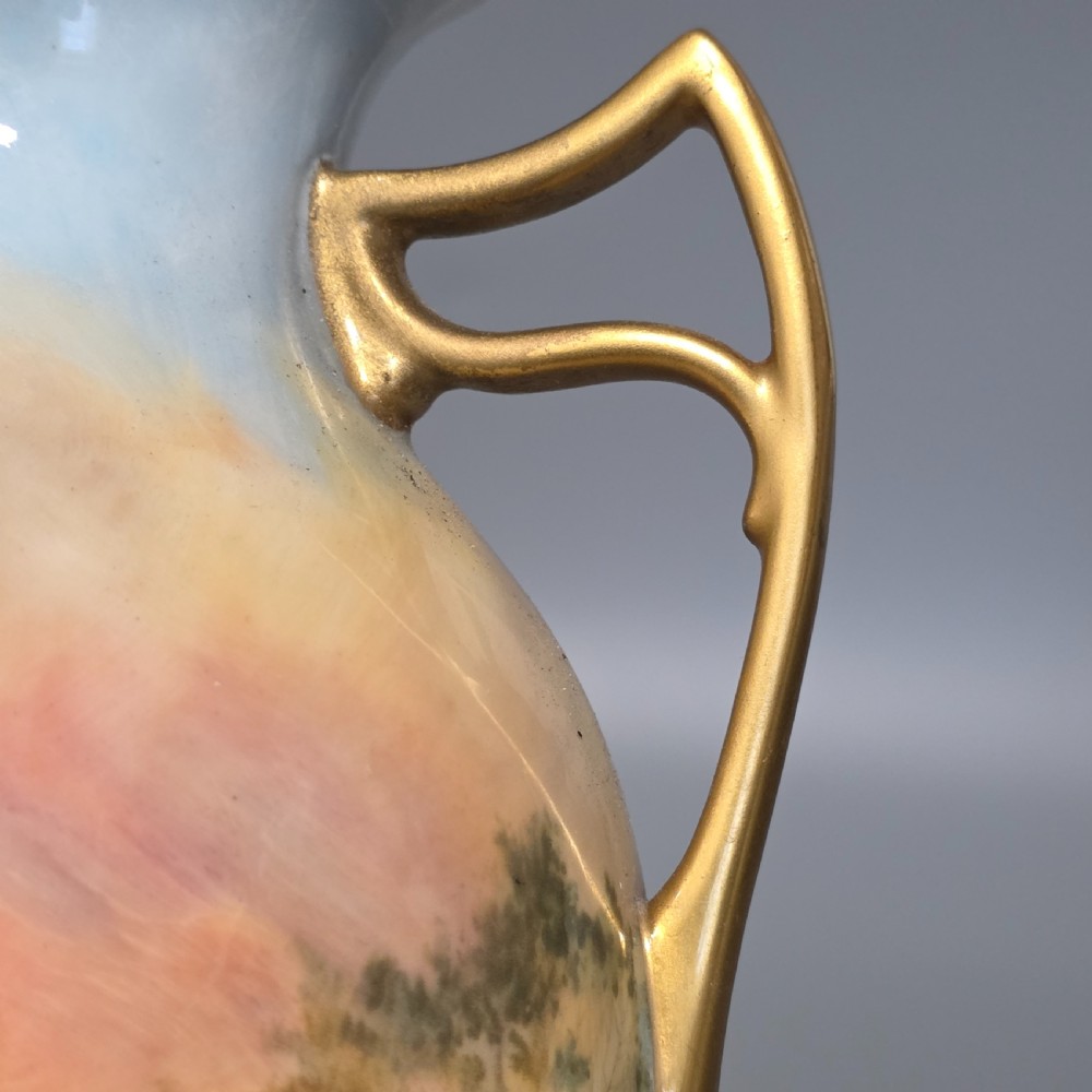 A tall porcelain vase featuring twin gilded handles and a handpainted landscape scene depicting Windsor Castle against a soft sunset sky. View IX
