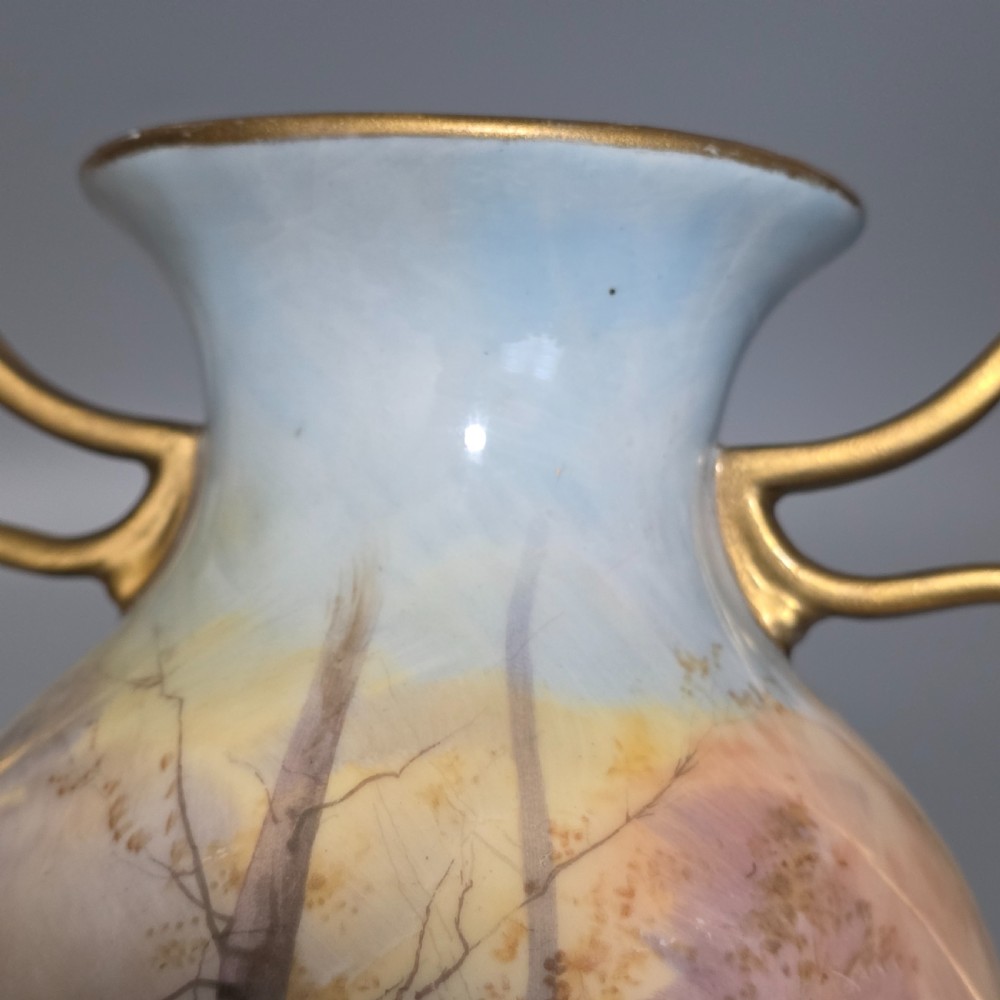 A tall porcelain vase featuring twin gilded handles and a handpainted landscape scene depicting Windsor Castle against a soft sunset sky. View XII