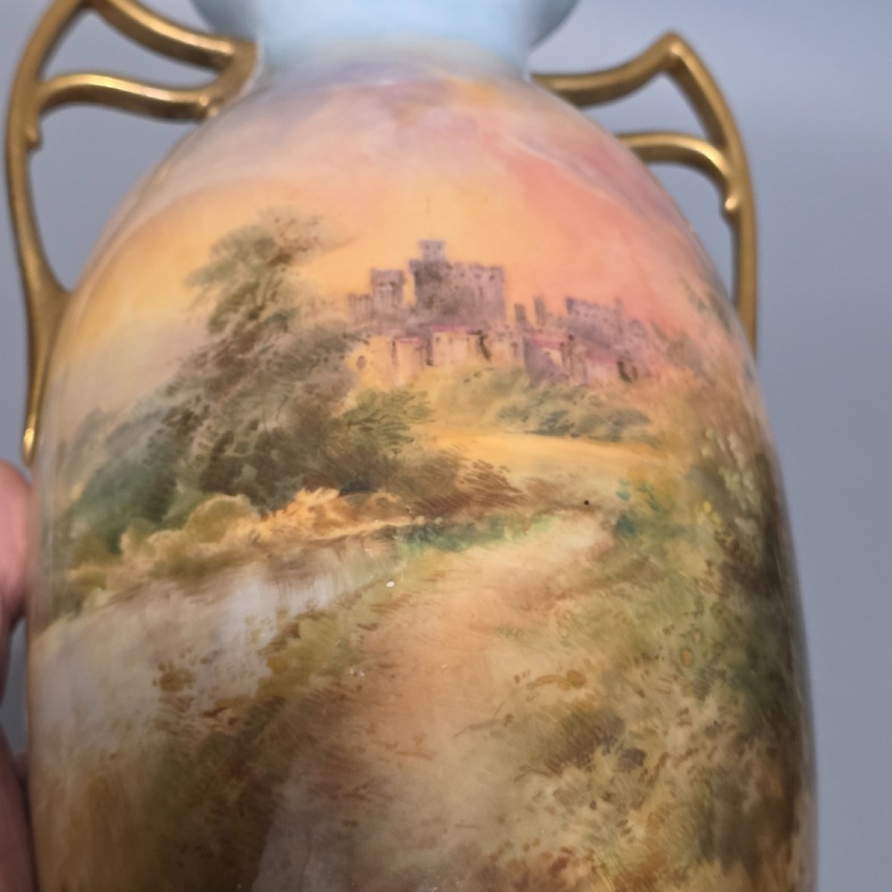 A tall porcelain vase featuring twin gilded handles and a handpainted landscape scene depicting Windsor Castle against a soft sunset sky. View XV