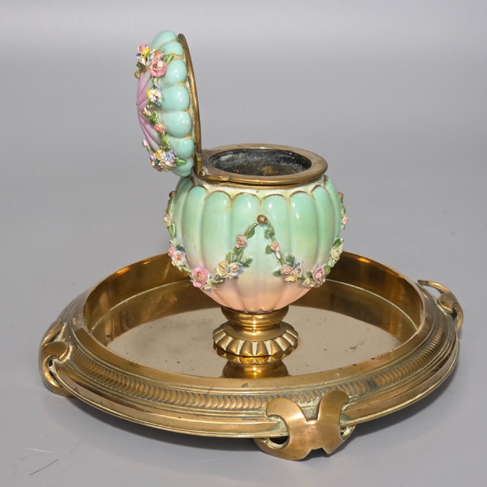 A fluted pastel green and pink porcelain inkwell decorated with applied floral swags, mounted on a turned brass pedestal within a circular brass tray base. View III