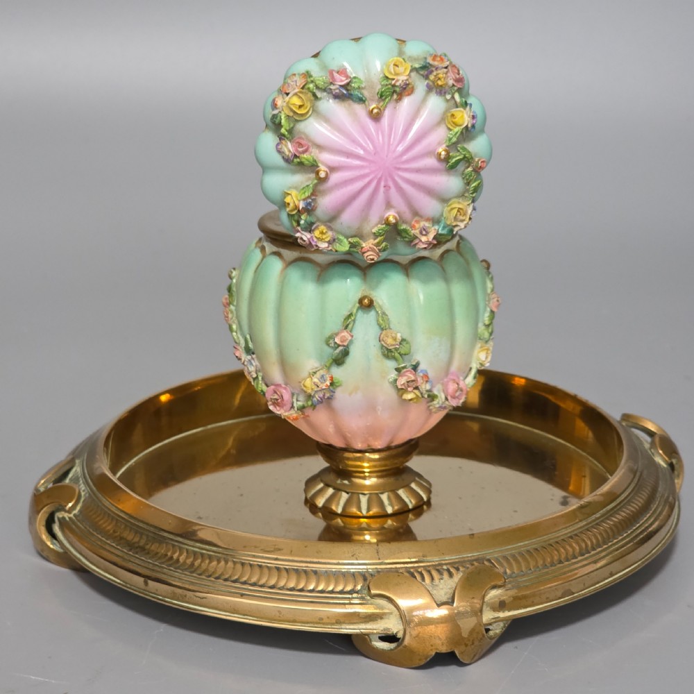 A fluted pastel green and pink porcelain inkwell decorated with applied floral swags, mounted on a turned brass pedestal within a circular brass tray base. View IV