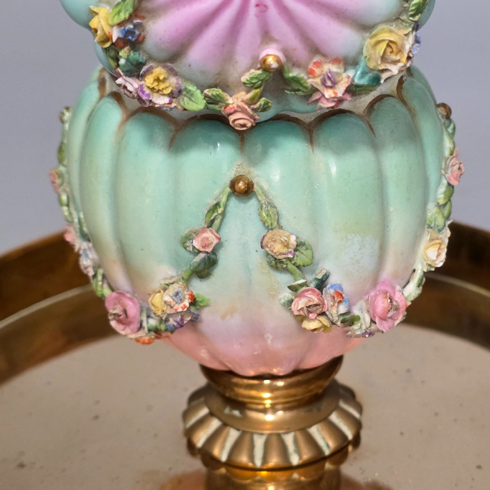 A fluted pastel green and pink porcelain inkwell decorated with applied floral swags, mounted on a turned brass pedestal within a circular brass tray base. View VI