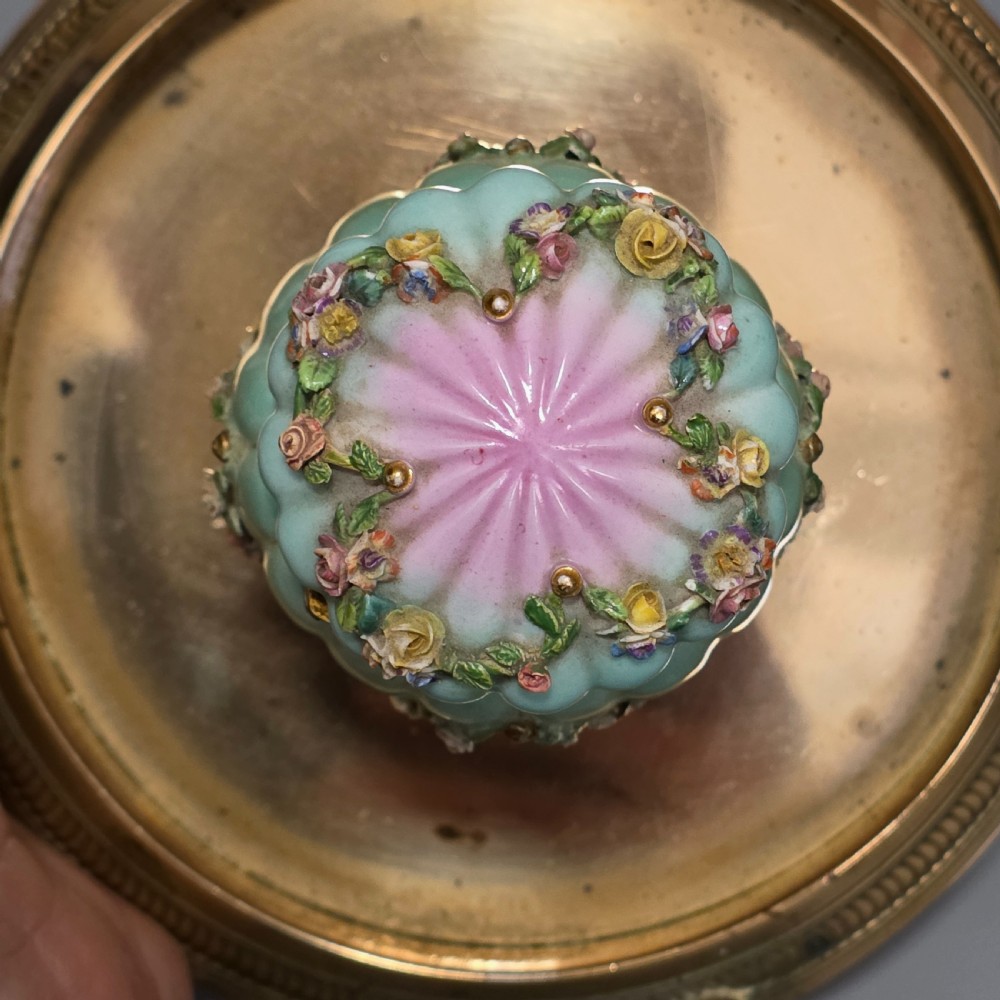 A fluted pastel green and pink porcelain inkwell decorated with applied floral swags, mounted on a turned brass pedestal within a circular brass tray base. View X