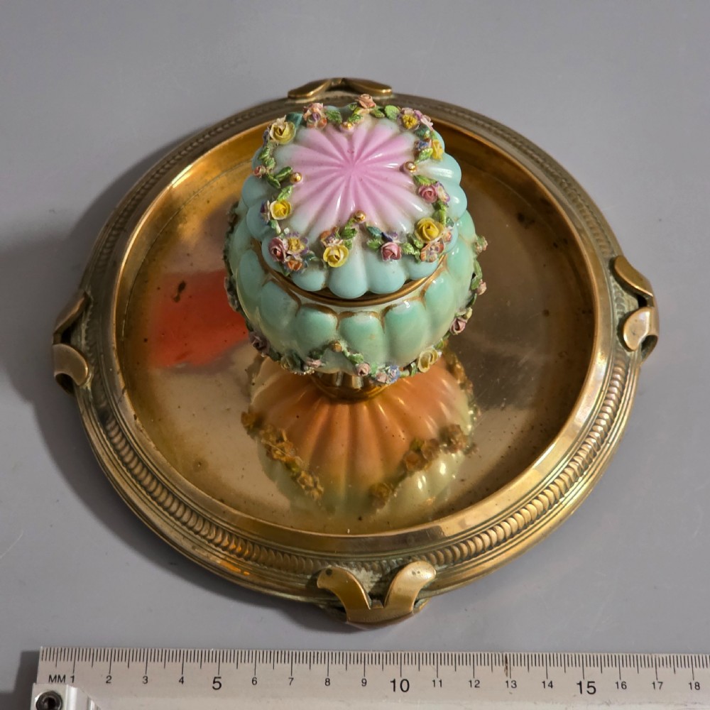 A fluted pastel green and pink porcelain inkwell decorated with applied floral swags, mounted on a turned brass pedestal within a circular brass tray base. View XI