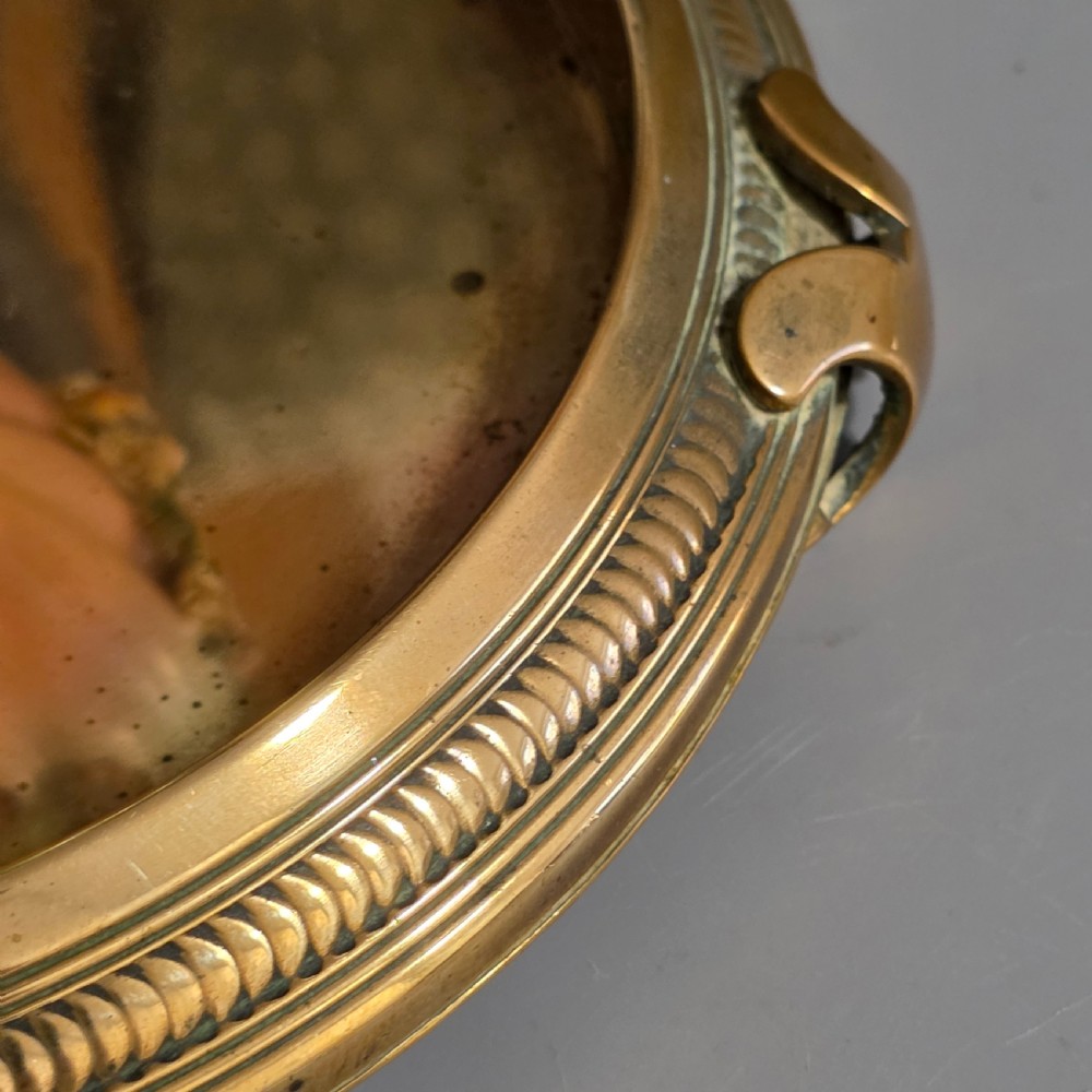 A fluted pastel green and pink porcelain inkwell decorated with applied floral swags, mounted on a turned brass pedestal within a circular brass tray base. View XII