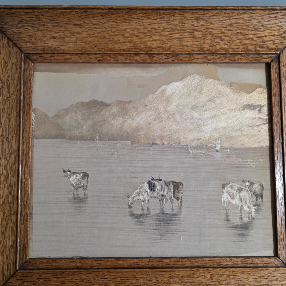 A framed Chinese silk embroidery panel depicting cattle standing in water in front of a mountainous background, presented in a wide oak frame. View II