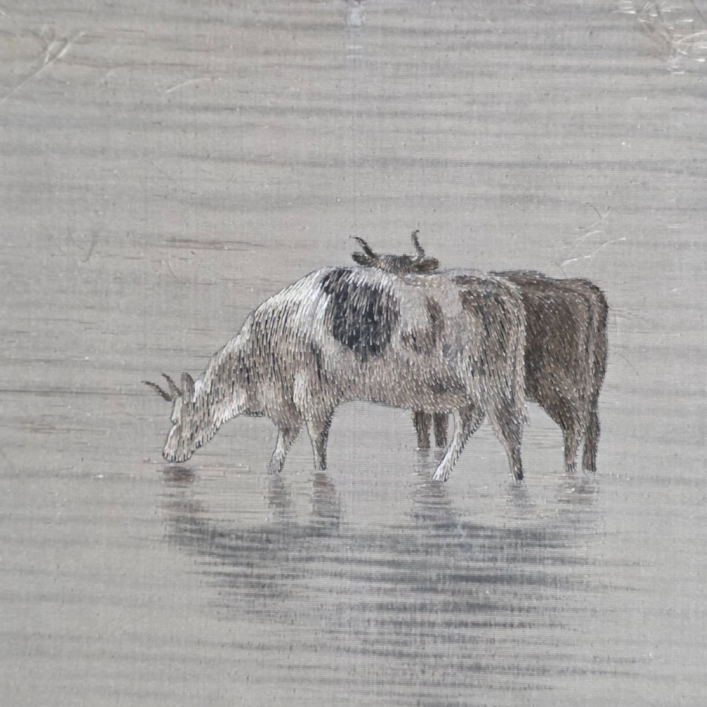 A framed Chinese silk embroidery panel depicting cattle standing in water in front of a mountainous background, presented in a wide oak frame. View V
