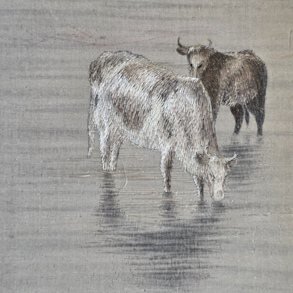 A framed Chinese silk embroidery panel depicting cattle standing in water in front of a mountainous background, presented in a wide oak frame. View VII
