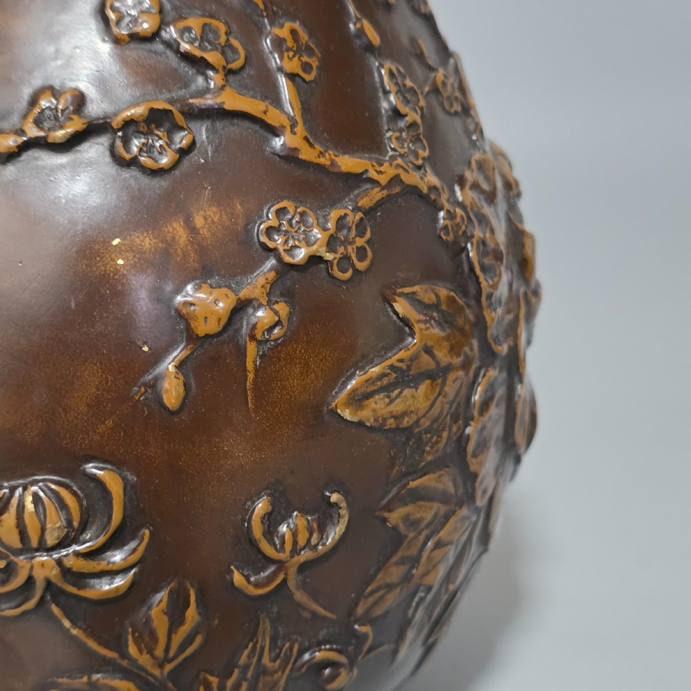 A dark brown patinated bronze vase featuring raised high-relief floral carvings of large peonies and chrysanthemums. View X