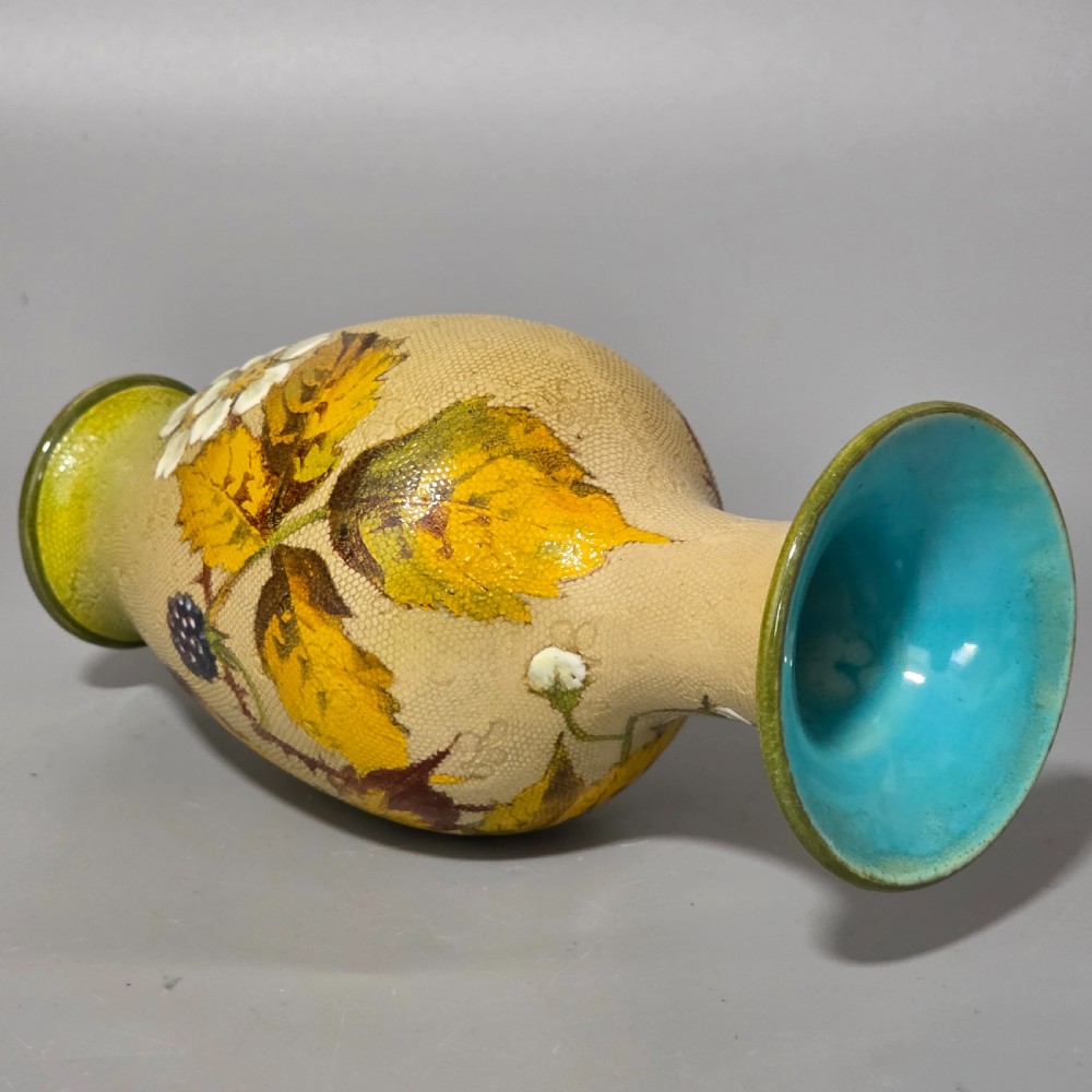 A baluster-shaped Doulton Lambeth ceramic vase featuring a textured lace-patterned buff background painted with botanical autumn leaves and blackberries, finished with a bright turquoise interior rim. View V