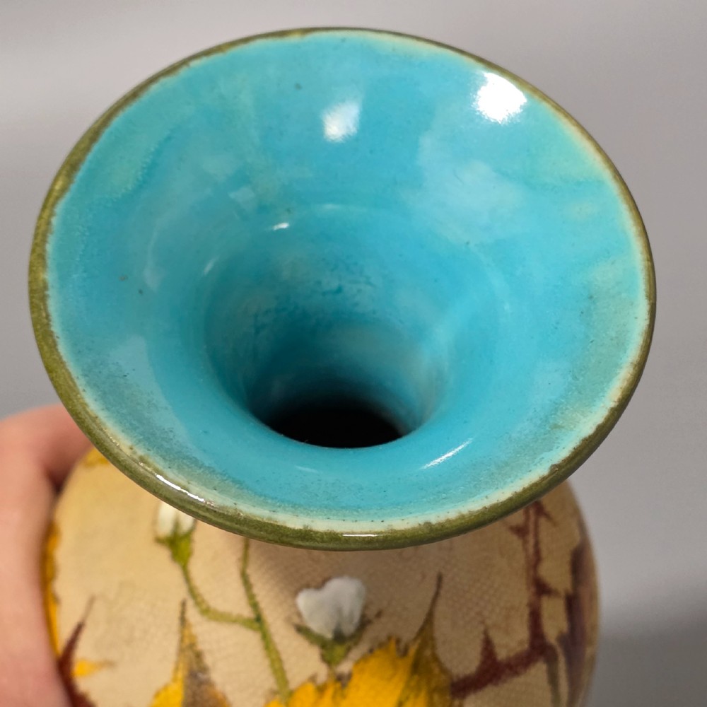 A baluster-shaped Doulton Lambeth ceramic vase featuring a textured lace-patterned buff background painted with botanical autumn leaves and blackberries, finished with a bright turquoise interior rim. View VII