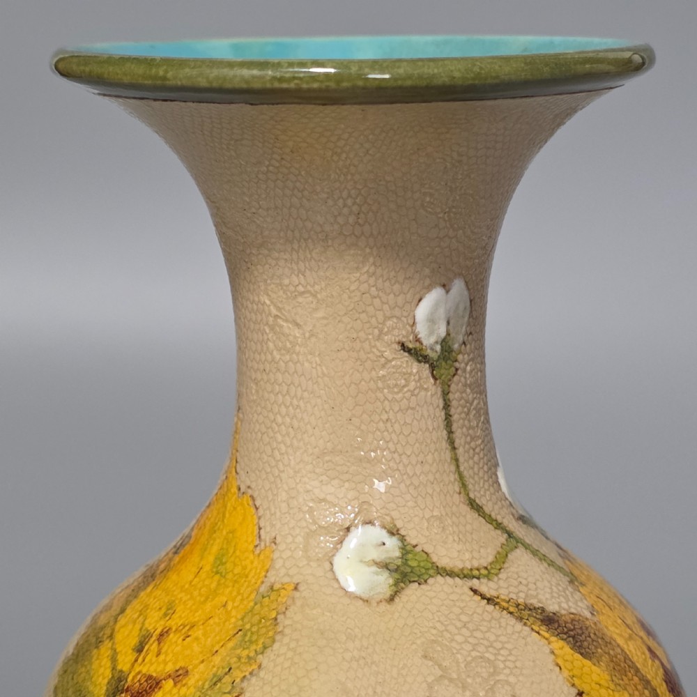 A baluster-shaped Doulton Lambeth ceramic vase featuring a textured lace-patterned buff background painted with botanical autumn leaves and blackberries, finished with a bright turquoise interior rim. View X