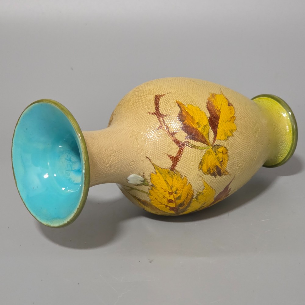 A baluster-shaped Doulton Lambeth ceramic vase featuring a textured lace-patterned buff background painted with botanical autumn leaves and blackberries, finished with a bright turquoise interior rim. View XII