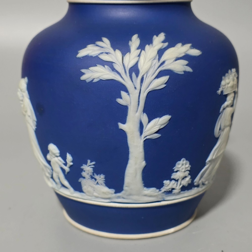 A cobalt blue stoneware jug featuring white raised neoclassical figures in relief with a high arched handle and curved spout. View VI