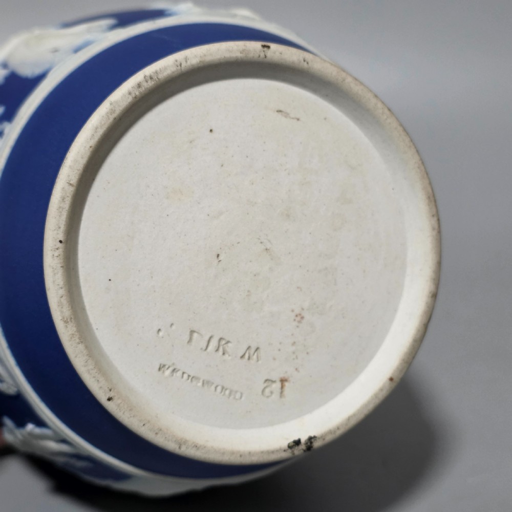 A cobalt blue stoneware jug featuring white raised neoclassical figures in relief with a high arched handle and curved spout. View XI