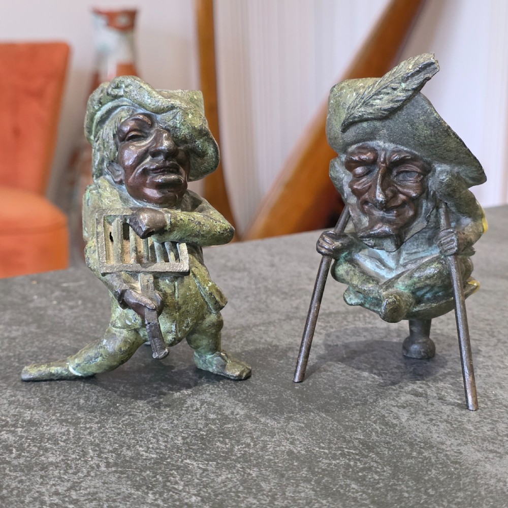 A pair of early twentieth-century French patinated bronze candle holders cast in the form of grotesque satirical caricature figures.
