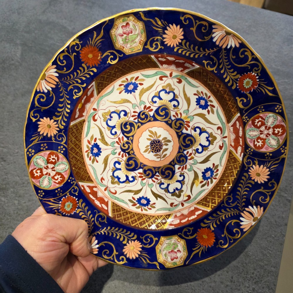 A circular Victorian Ashworth ironstone plate decorated with a rich cobalt blue rim, intricate gilt foliage, and a central Imari floral motif in iron red, blue, and gold.