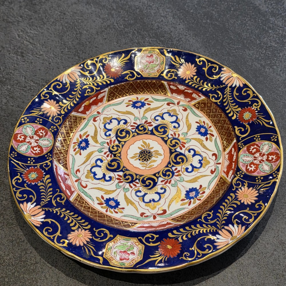 A circular Victorian Ashworth ironstone plate decorated with a rich cobalt blue rim, intricate gilt foliage, and a central Imari floral motif in iron red, blue, and gold. View II