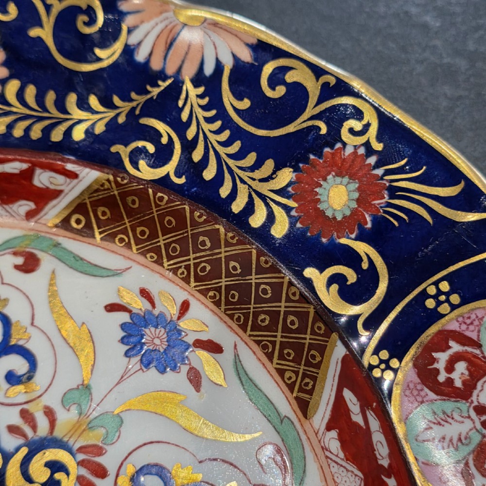 A circular Victorian Ashworth ironstone plate decorated with a rich cobalt blue rim, intricate gilt foliage, and a central Imari floral motif in iron red, blue, and gold. View IV