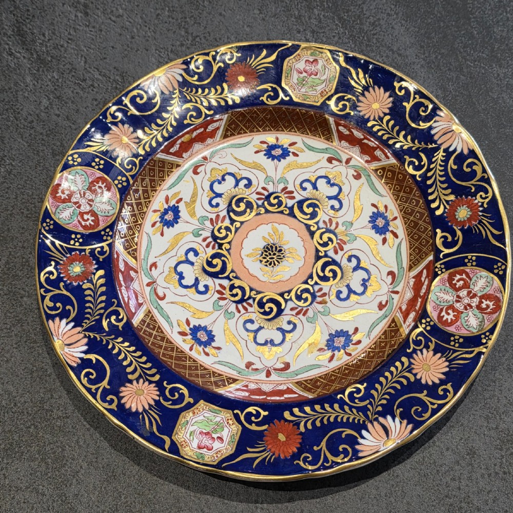 A circular Victorian Ashworth ironstone plate decorated with a rich cobalt blue rim, intricate gilt foliage, and a central Imari floral motif in iron red, blue, and gold. View VII