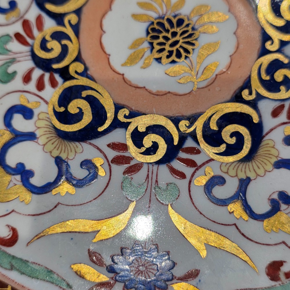 A circular Victorian Ashworth ironstone plate decorated with a rich cobalt blue rim, intricate gilt foliage, and a central Imari floral motif in iron red, blue, and gold. View IX