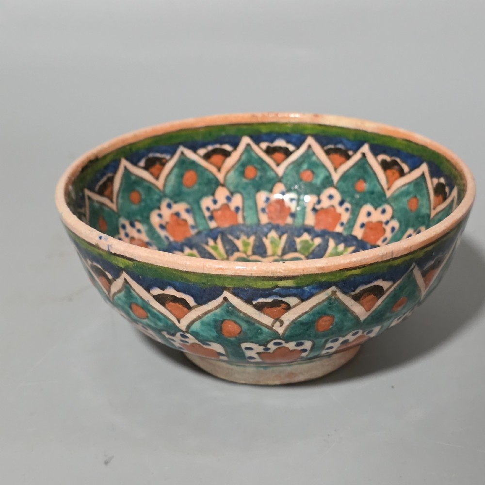 A circular hand-painted antique Middle Eastern ceramic bowl decorated with turquoise, cobalt blue, and terracotta geometric motifs. View IV