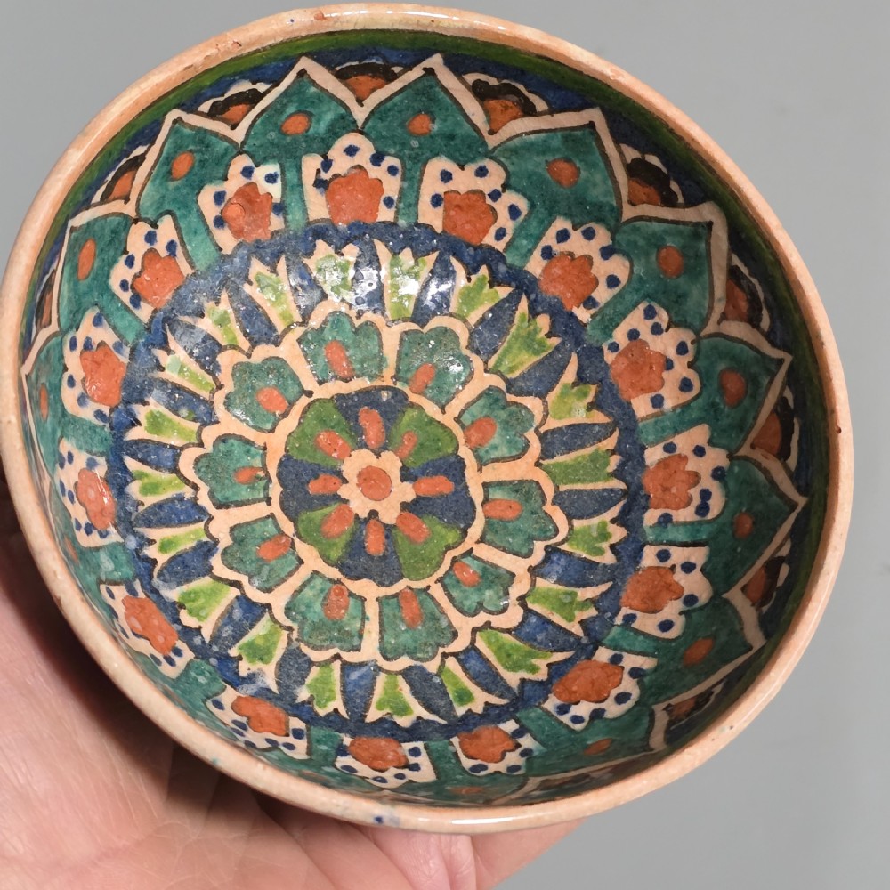 A circular hand-painted antique Middle Eastern ceramic bowl decorated with turquoise, cobalt blue, and terracotta geometric motifs. View V