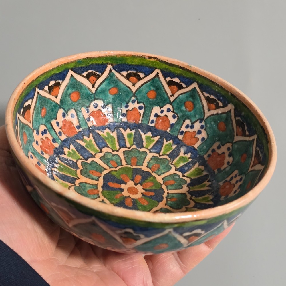 A circular hand-painted antique Middle Eastern ceramic bowl decorated with turquoise, cobalt blue, and terracotta geometric motifs. View VI