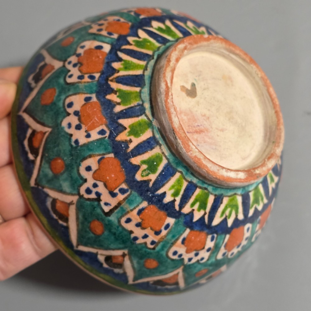 A circular hand-painted antique Middle Eastern ceramic bowl decorated with turquoise, cobalt blue, and terracotta geometric motifs. View VIII