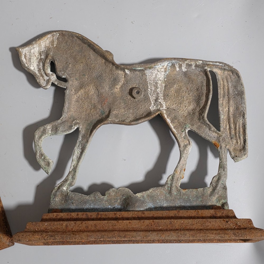 A pair of 19th-century cast iron and brass doorstops featuring prancing horses mounted on stepped rectangular bases with aged patina. View II