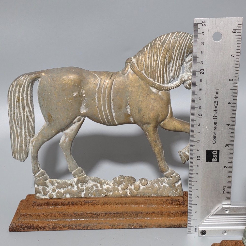 A pair of 19th-century cast iron and brass doorstops featuring prancing horses mounted on stepped rectangular bases with aged patina. View VI