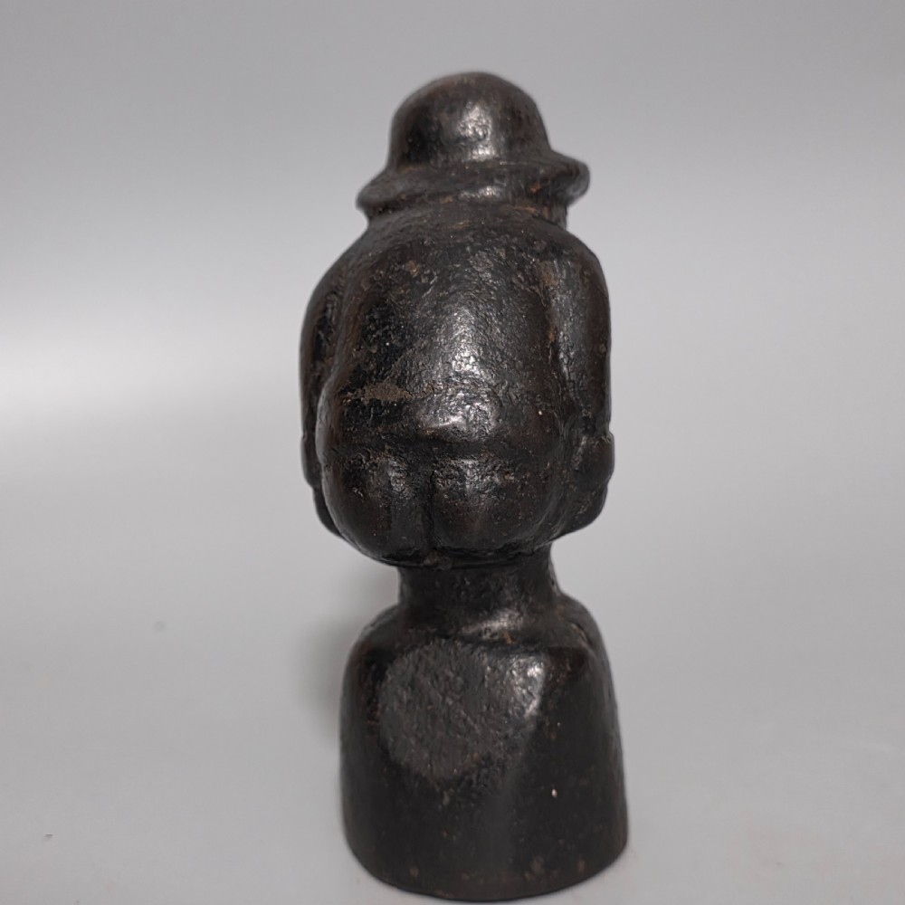 A nineteenth-century dark cast iron paperweight shaped as a crouching male figure in a hat set upon a cylindrical pedestal. View V