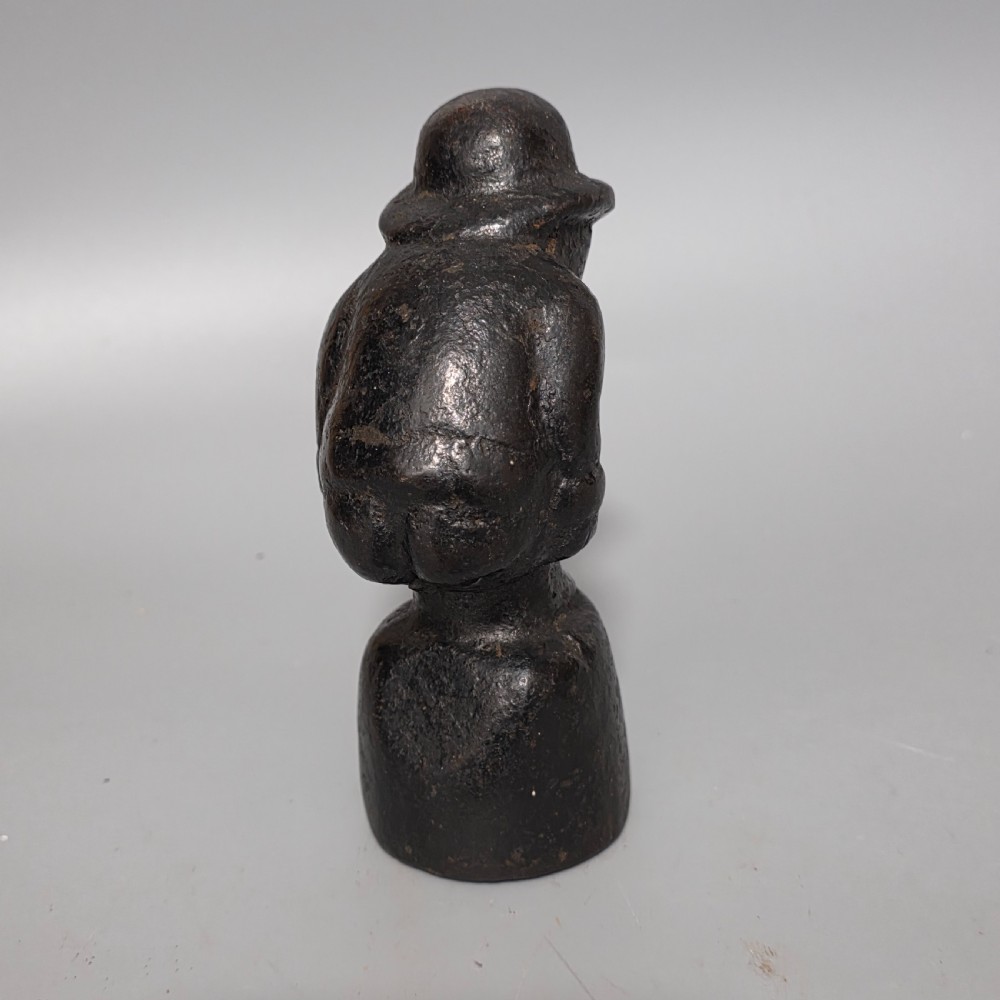 A nineteenth-century dark cast iron paperweight shaped as a crouching male figure in a hat set upon a cylindrical pedestal. View VIII