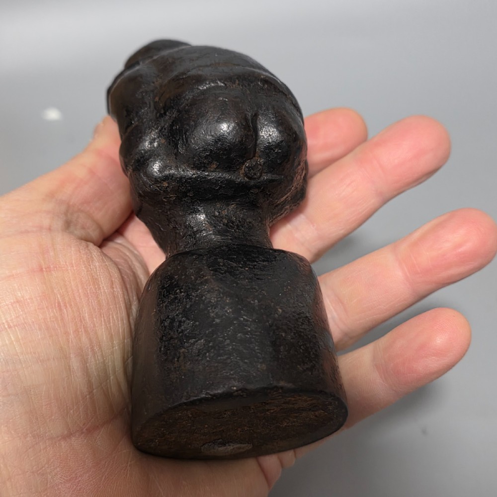 A nineteenth-century dark cast iron paperweight shaped as a crouching male figure in a hat set upon a cylindrical pedestal. View XIII