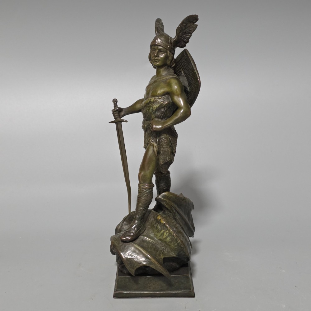 A patinated bronze sculpture depicting the mythical hero Siegfried standing victorious with a sword, winged helmet, and shield above a dragon base. View II