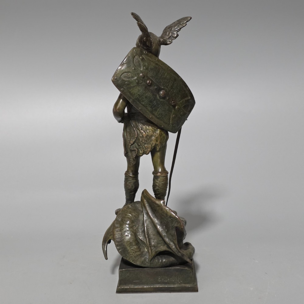 A patinated bronze sculpture depicting the mythical hero Siegfried standing victorious with a sword, winged helmet, and shield above a dragon base. View III