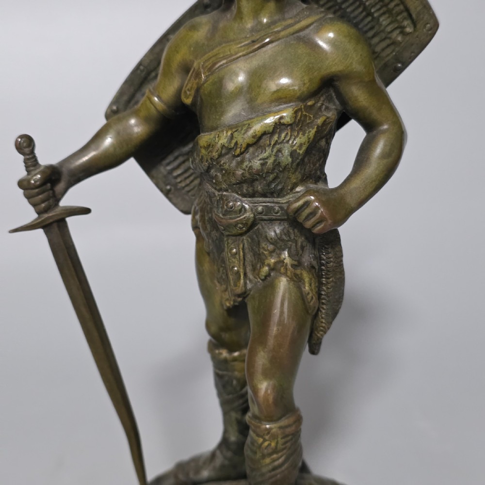 A patinated bronze sculpture depicting the mythical hero Siegfried standing victorious with a sword, winged helmet, and shield above a dragon base. View XI