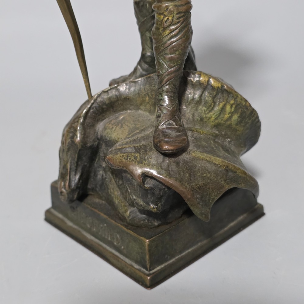 A patinated bronze sculpture depicting the mythical hero Siegfried standing victorious with a sword, winged helmet, and shield above a dragon base. View XII