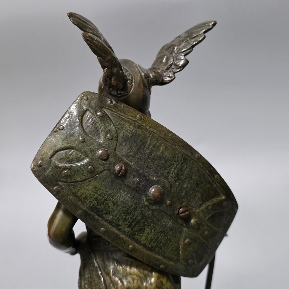 A patinated bronze sculpture depicting the mythical hero Siegfried standing victorious with a sword, winged helmet, and shield above a dragon base. View XVIII