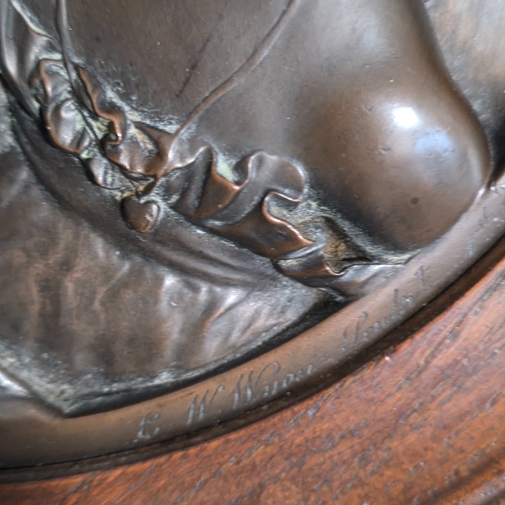 A circular Victorian bronze relief plaque depicting two young children in high relief, housed within a turned oak frame. View IV
