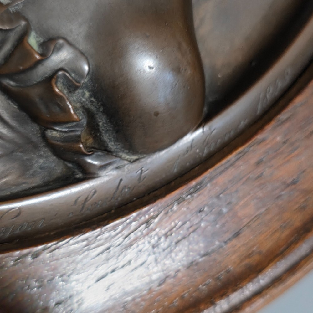 A circular Victorian bronze relief plaque depicting two young children in high relief, housed within a turned oak frame. View V