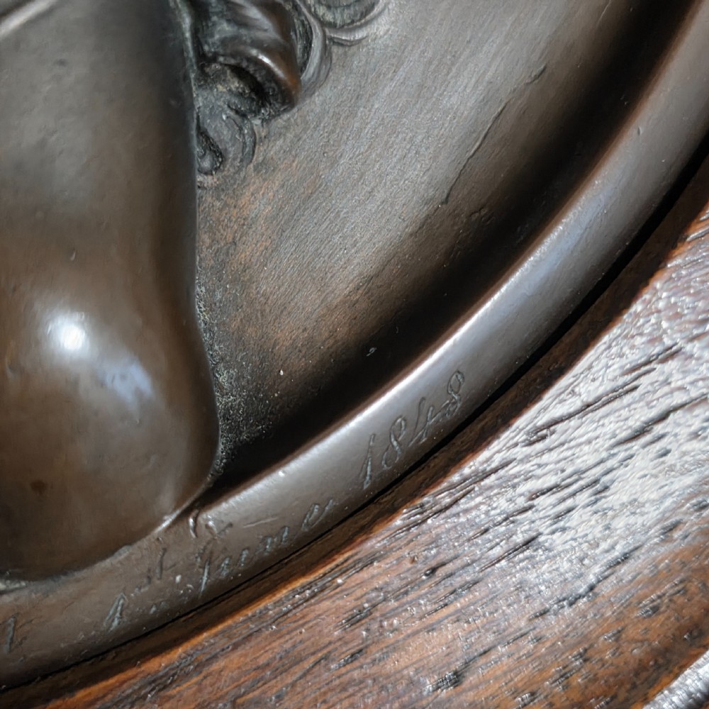 A circular Victorian bronze relief plaque depicting two young children in high relief, housed within a turned oak frame. View VI