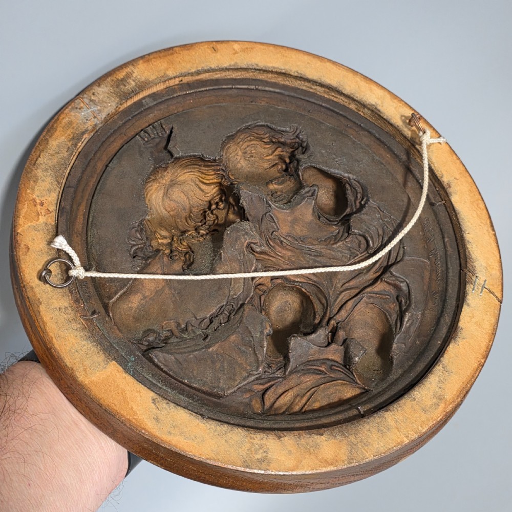 A circular Victorian bronze relief plaque depicting two young children in high relief, housed within a turned oak frame. View XI